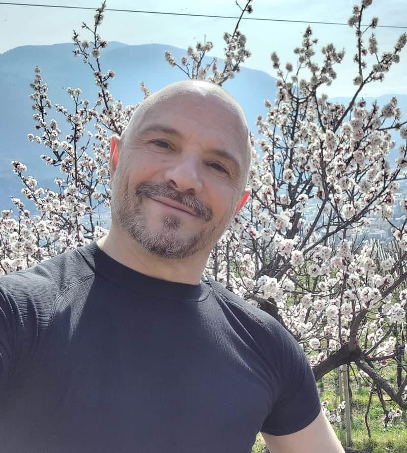 Uomo felice tra alberi di ciliegio in fiore, paesaggio primaverile sereno.